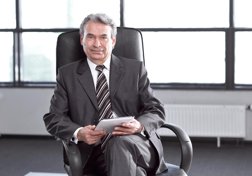 confident businessman with leather folder sitting office